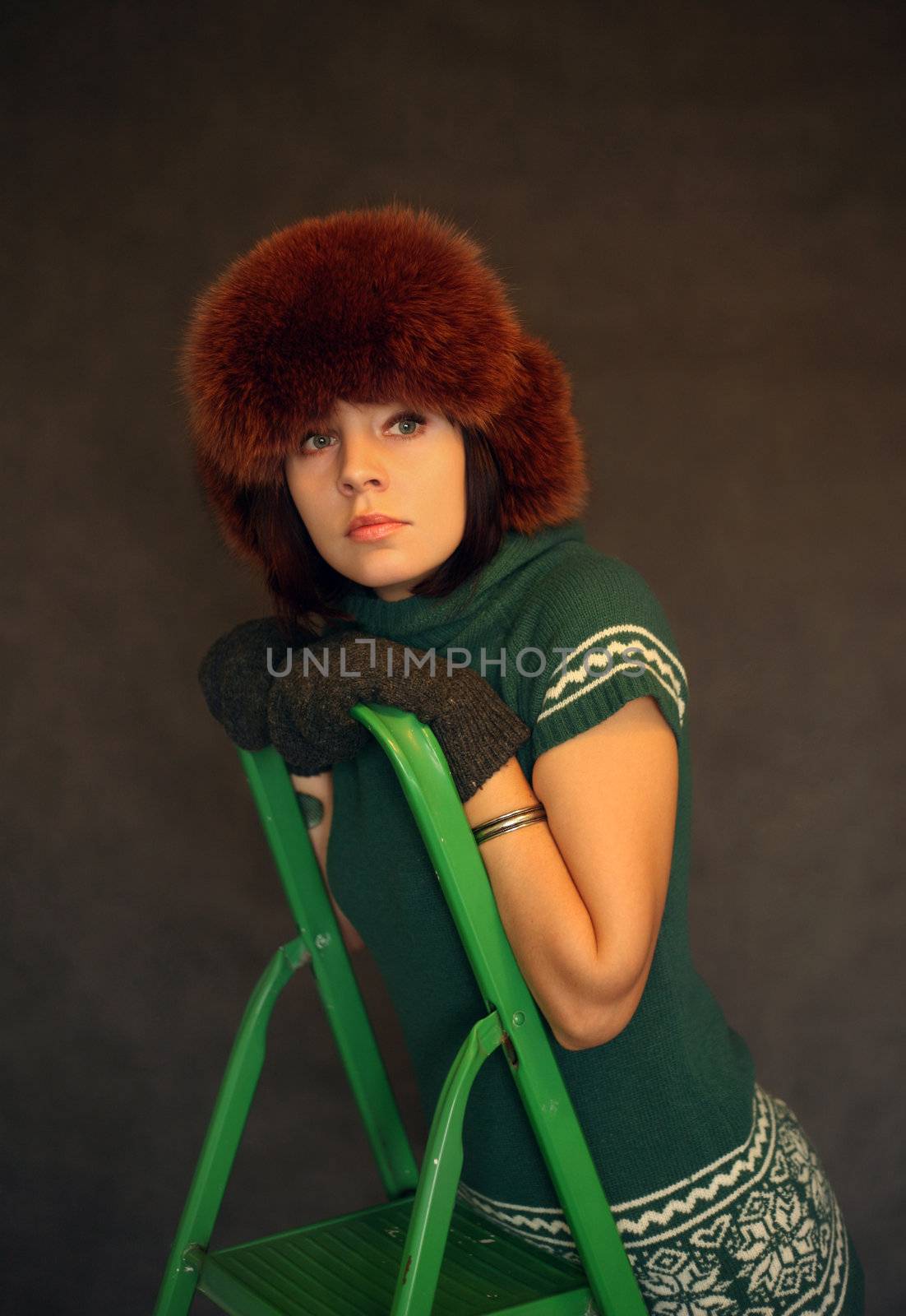 The beautiful girl in studio with a green step-ladder