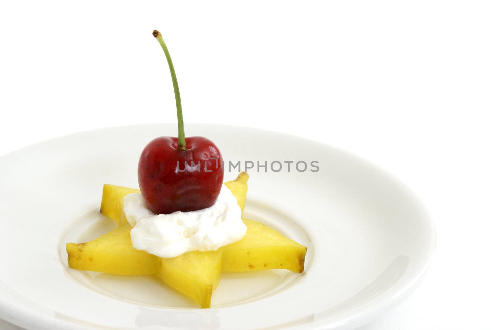 A piece of star-fruit with whipped cream and a cherry.