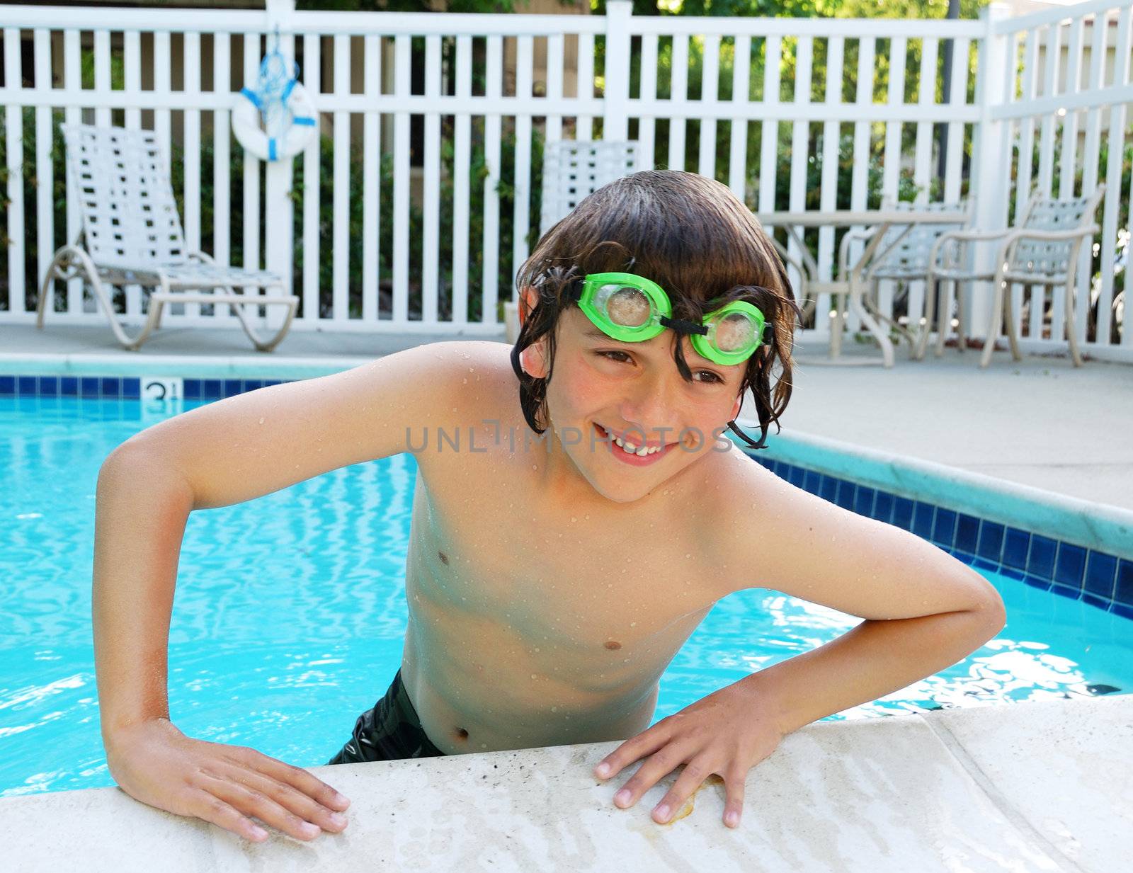 Teen boy with swimming goggles enjoying the pool.