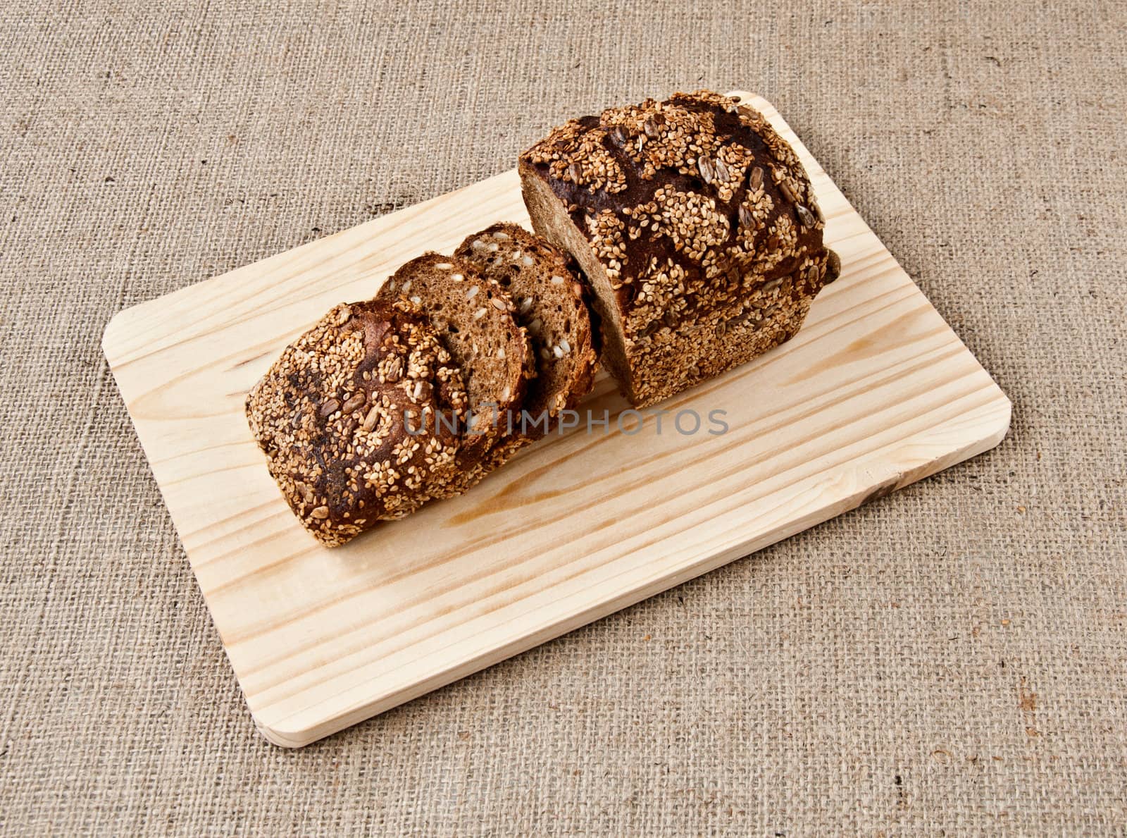 on the kitchen blackboard is sliced rye bread with grains on the background of coarse cloth