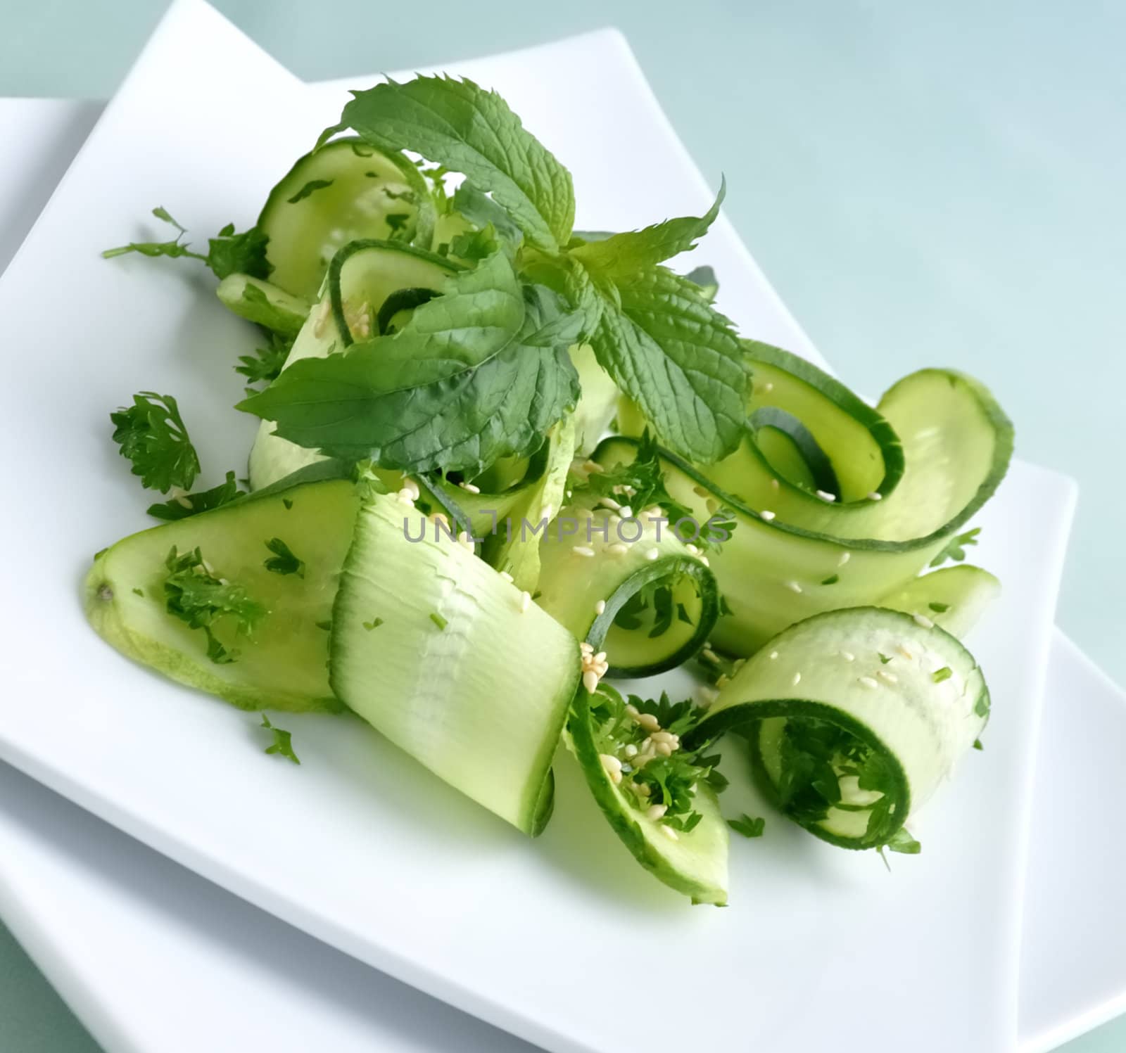 Salad of sliced green cucumbers with herbs and sesame seeds with mint leaves