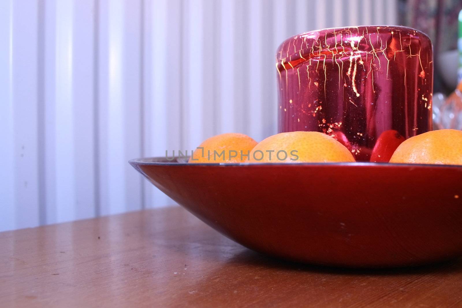festive candle and clementines in a red glass bowl