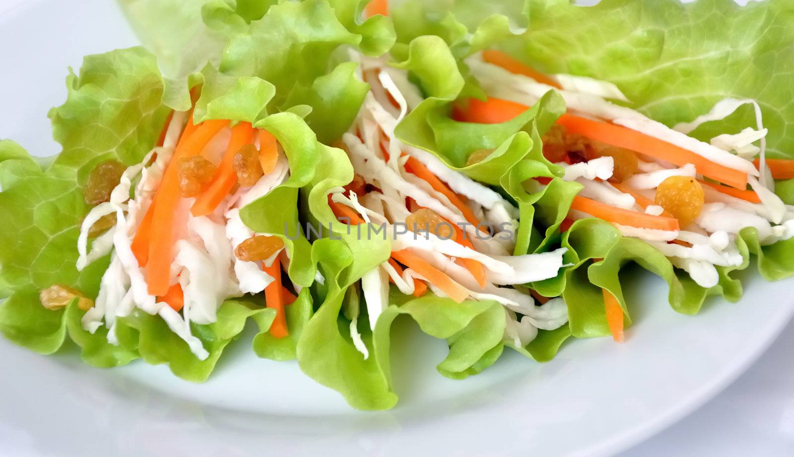 Salad with cabbage, carrots and raisins, wrapped in lettuce leaves