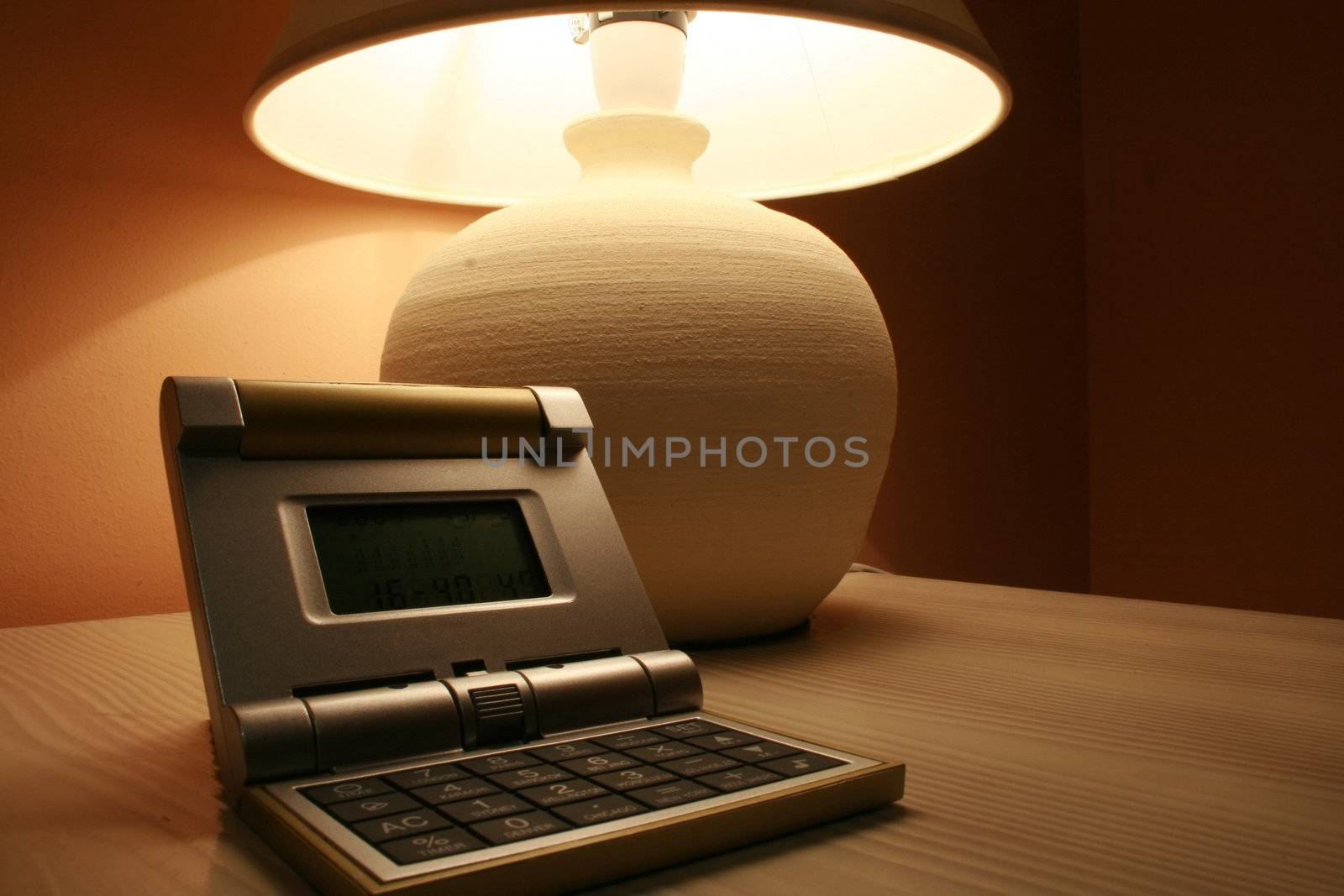 stone table lamp and travel clock on a wooden cabinet in the interior of a hotel bedroom