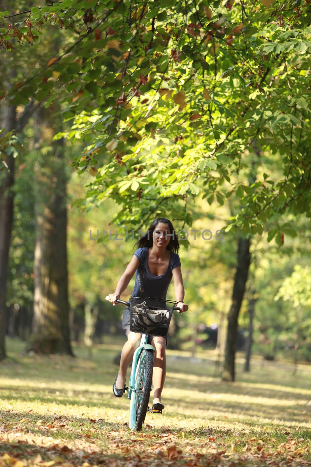 Young woman riding a bicycle in an early autumn forest. 
