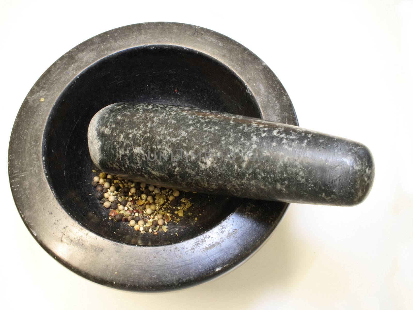 grinding pepper corns in a black granite pestle and mortar bowl isolated over a white background