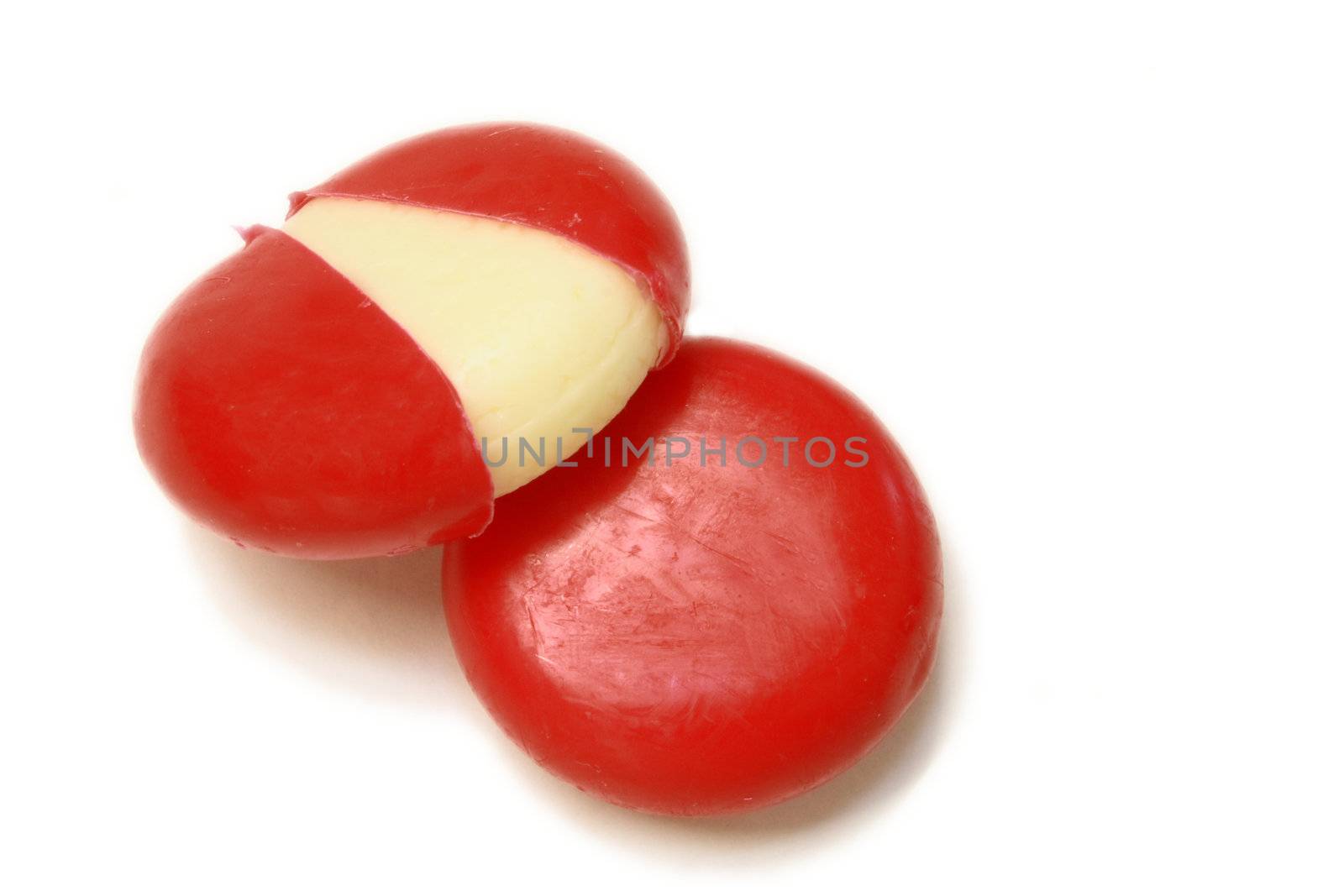 mini edam cheeses in a coating of red wax over a white background