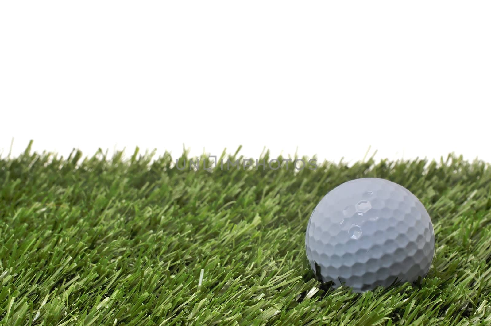 Closeup of golf ball  on grass with white background.