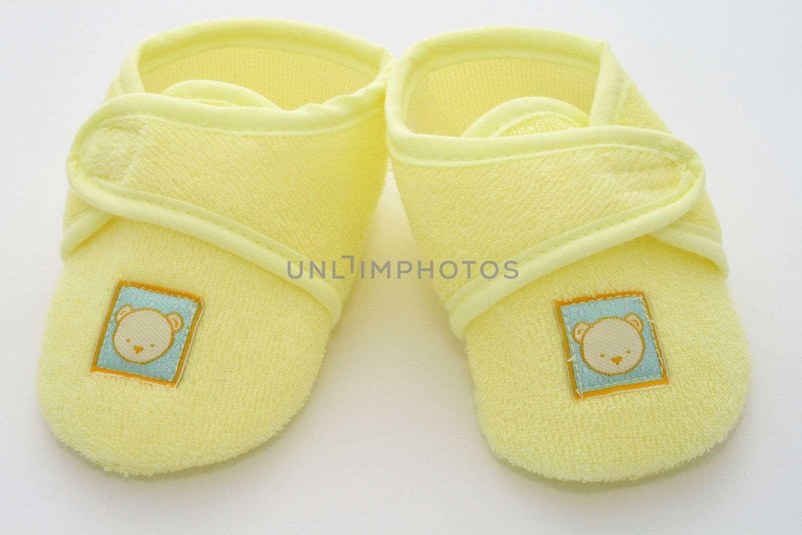 babies first pair of shoes in a yellow towelling material