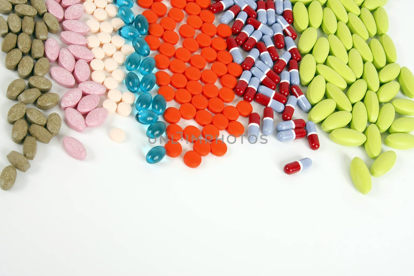 Many different pills lined up on a white background.