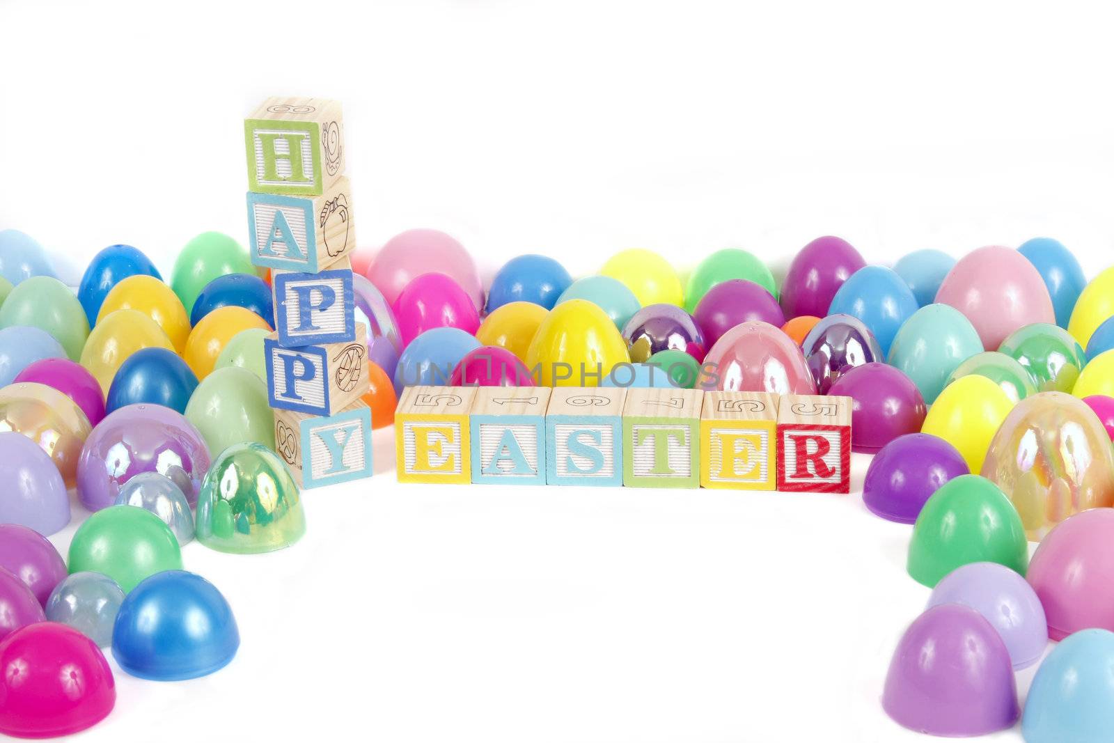 Childrens blocks spell Happy Easter with colorful plastic eggs on a white background.