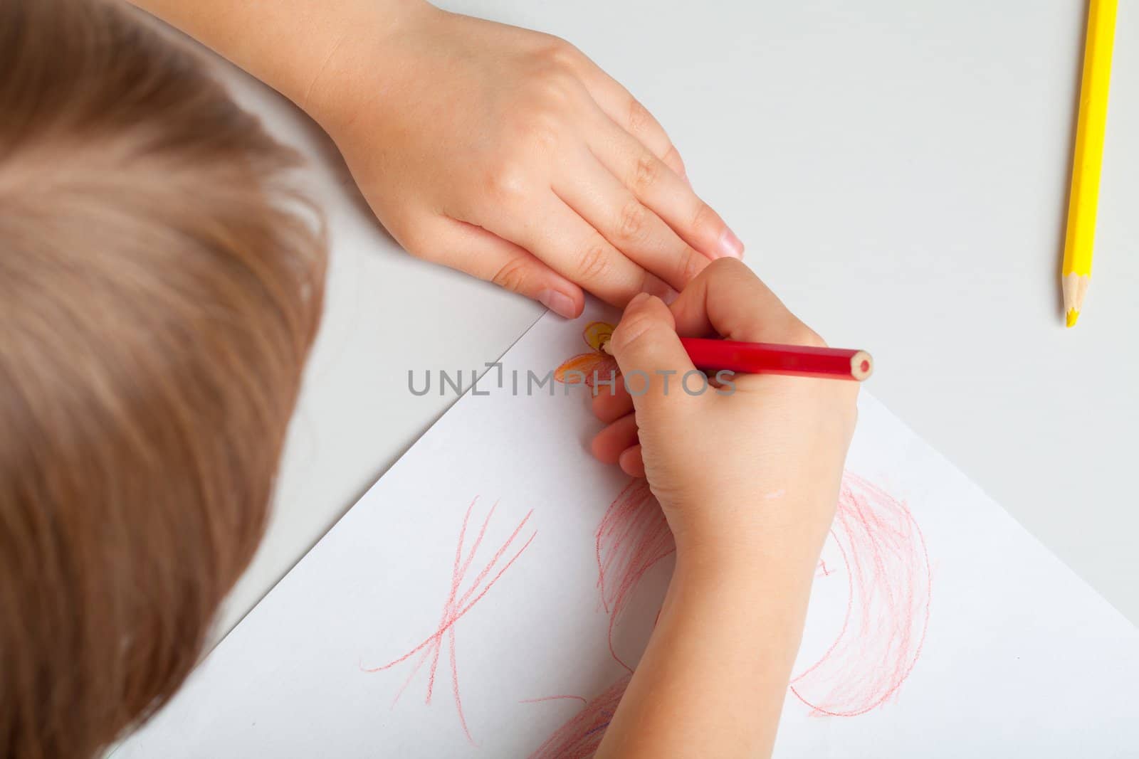 The child draws a picture with crayons. The concept of teaching drawing, children's creativity