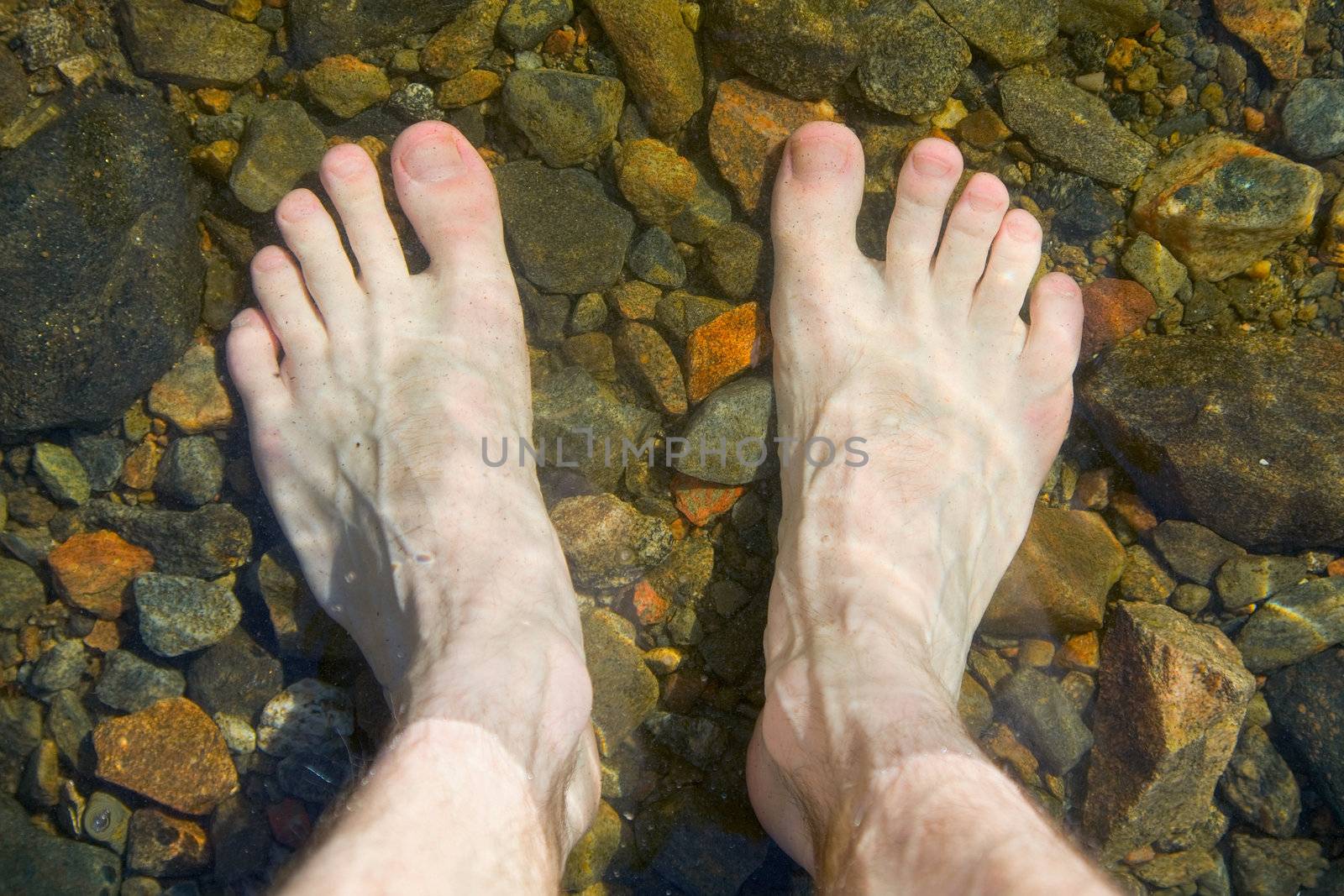 Bare feet on shoal of pure lake