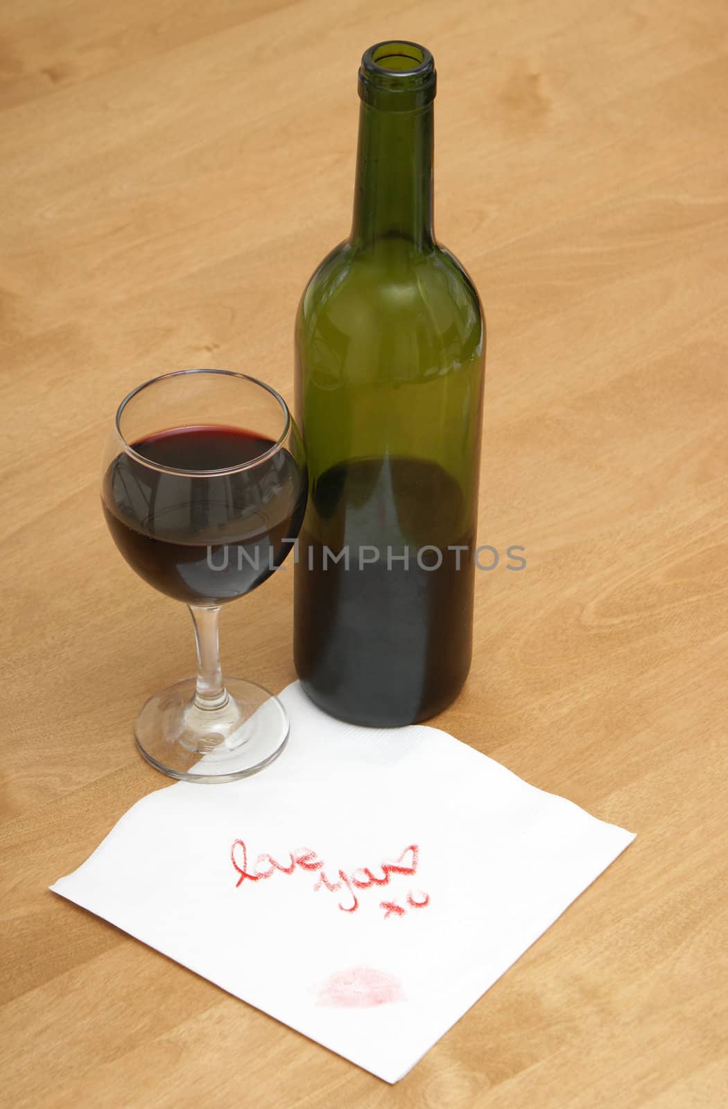 A woman writes a love note on a napkin, next to a bottle of wine.