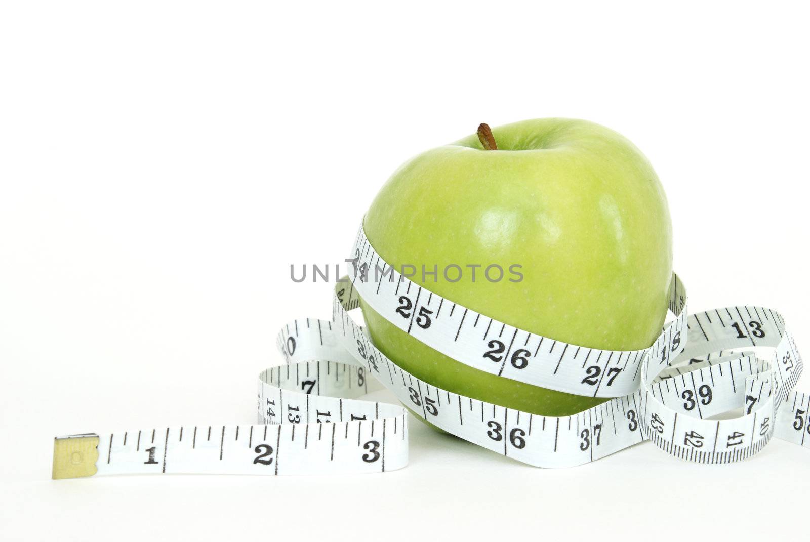 A green apple with a measuring tape wrapped around it for the concept of dieting.