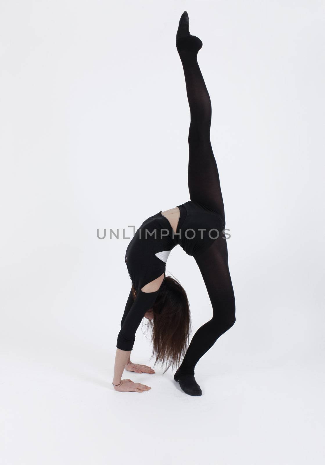 Young gymnast in black in studio with background