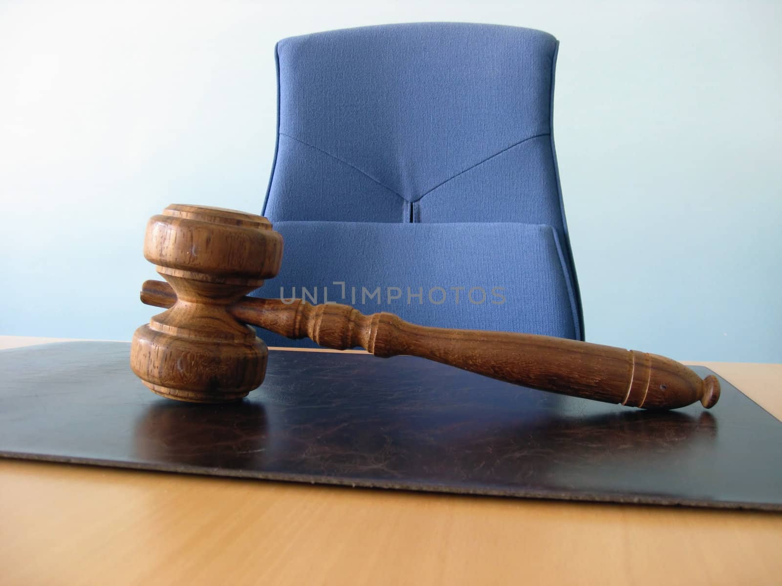 Old wooden gavel, a blue chair and a court desk