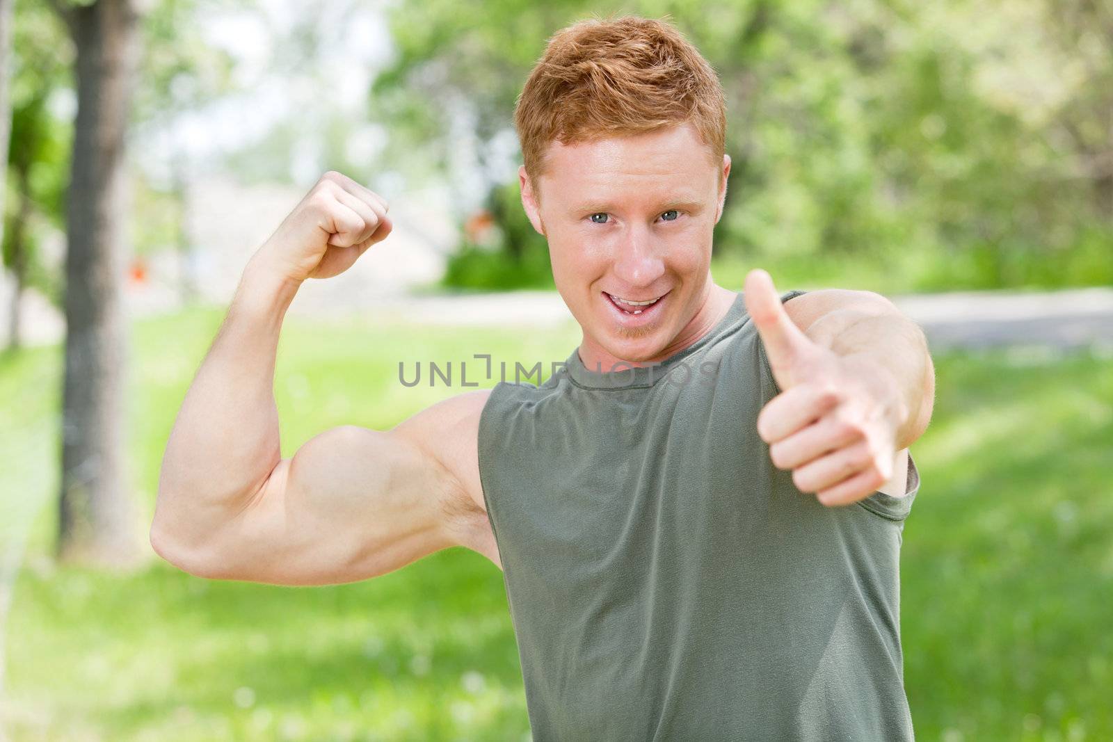 Man flexing and showing thumbs-up sign by leaf