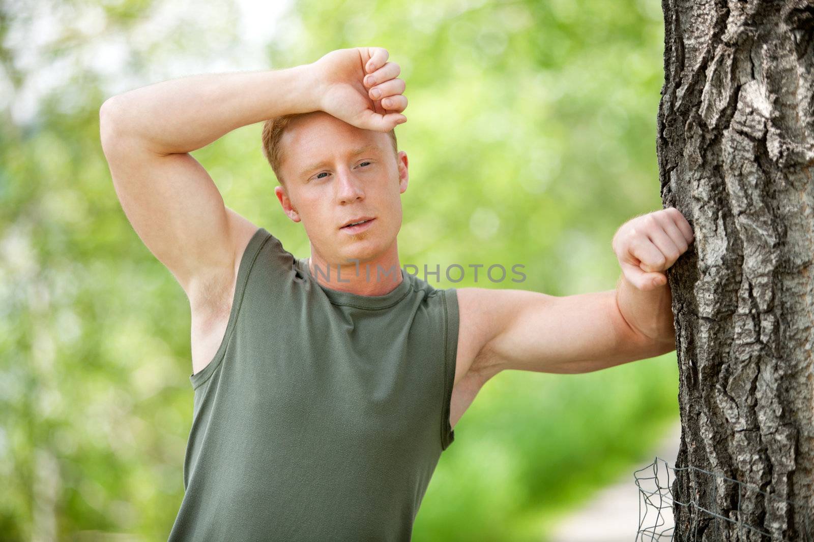 Tired man leaning on tree by leaf