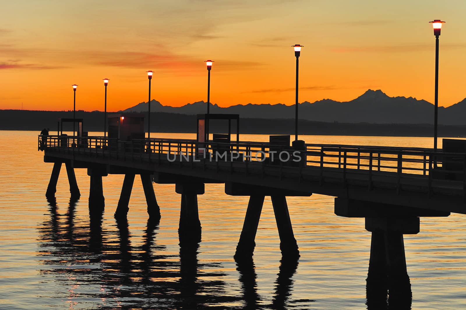 Marine pier at sunset, the Gulf of Puget Sound and the mountains of Olympic National Park, WA.