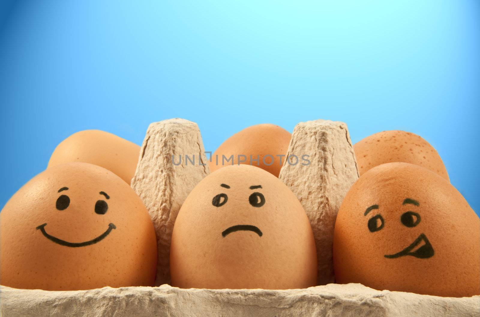 Close and low level of several brown eggs with painted faces against blue light effect background