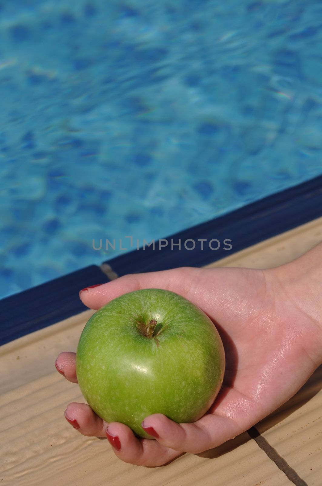 woman holding a green apple at the pool side as a diet concept