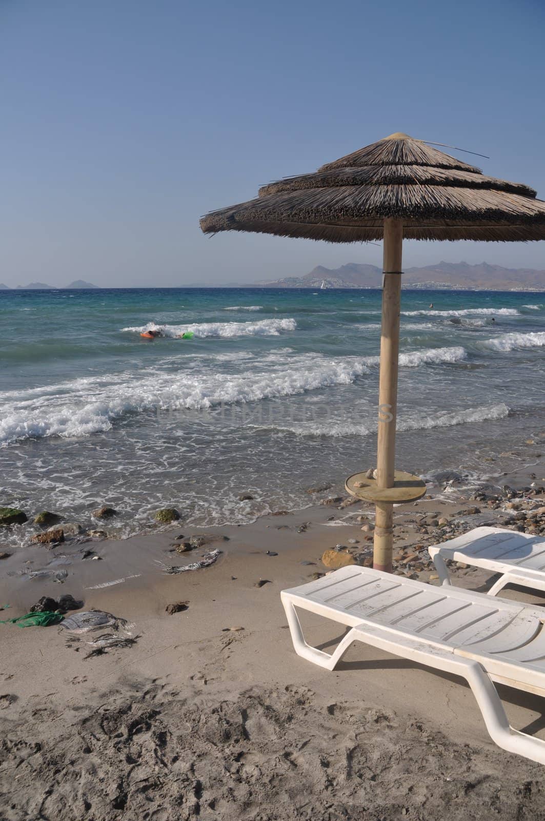 beautiful beach with umbrella and chairs in Kos, Greece (Turkey on the background)