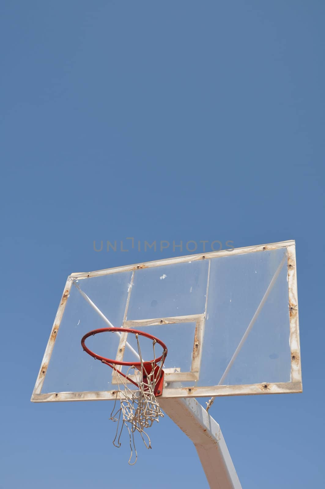 old outdoor basketball hoop against blue sky background