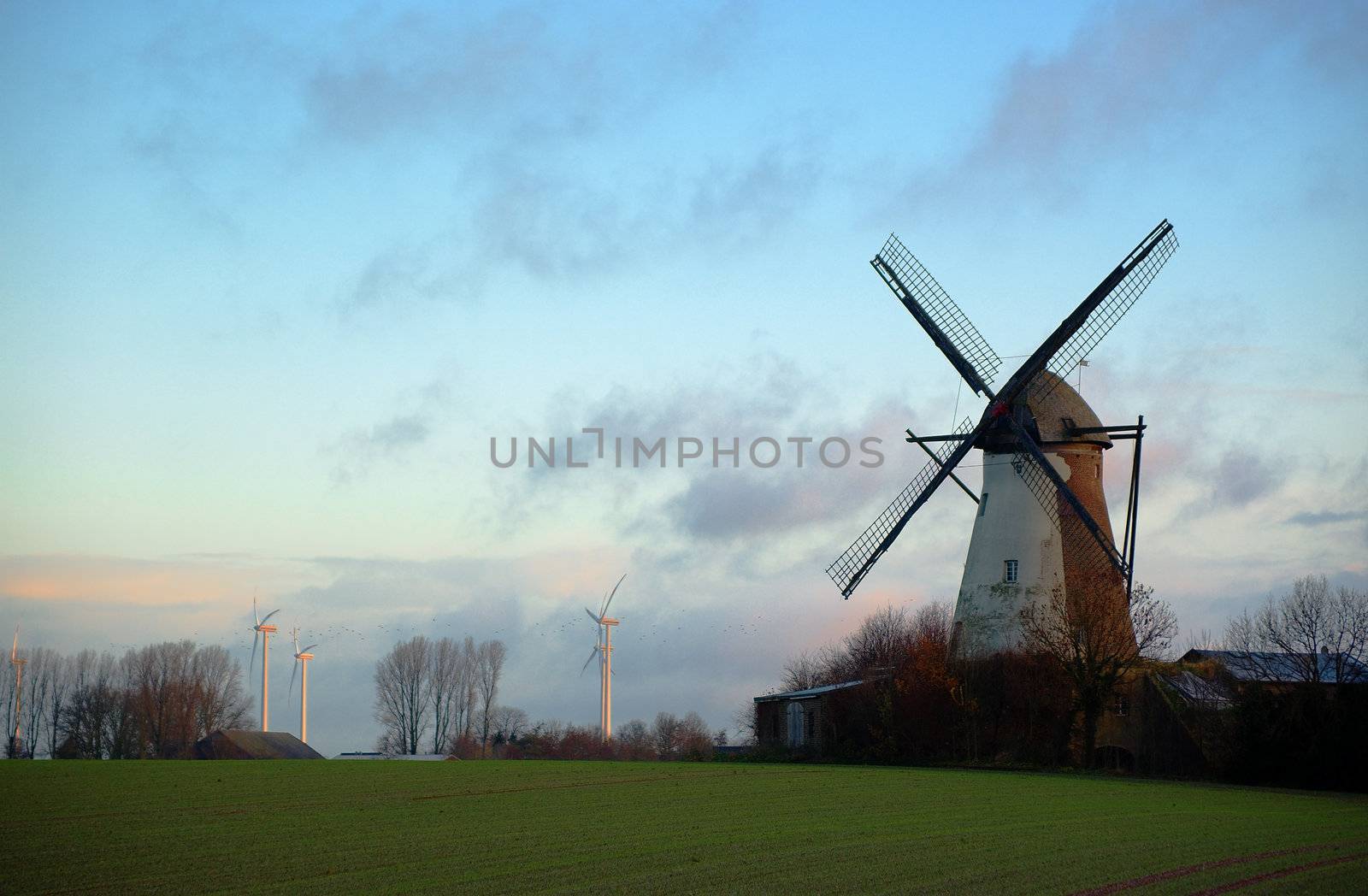 Morning light, traditional windmill in the foreground and modern windmill generators on a background