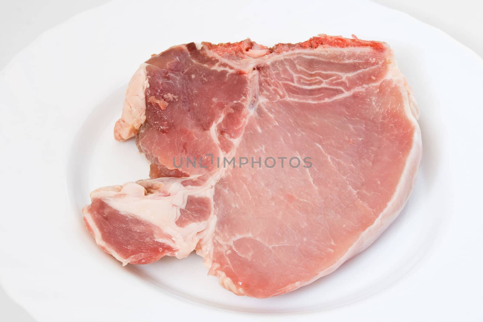 fresh raw pork chop on a white plate 