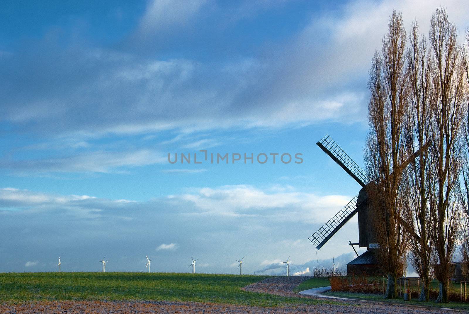 Traditional windmill in the foreground and modern windmill generators on a background