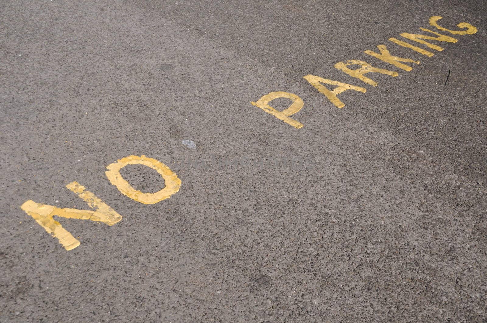 yellow painted no parking sign on the asphalt