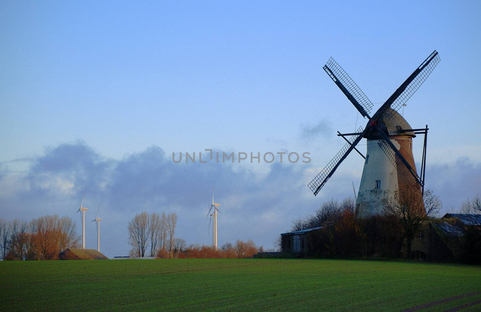Morning light, traditional windmill in the foreground and modern windmill generators on a background
