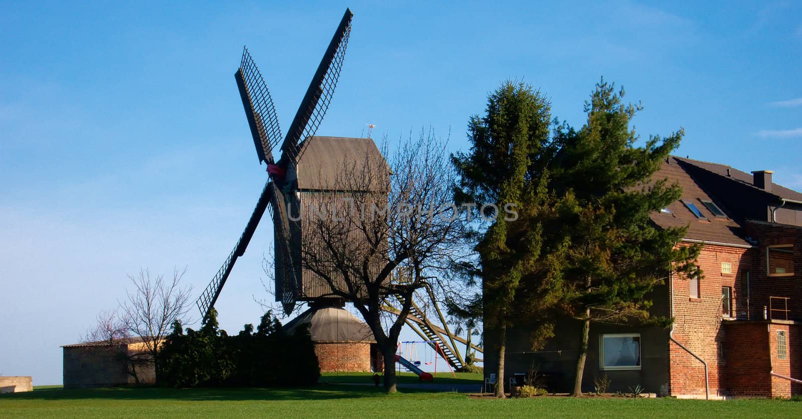 Morning light, traditional windmill  and house, green grass and blue sky