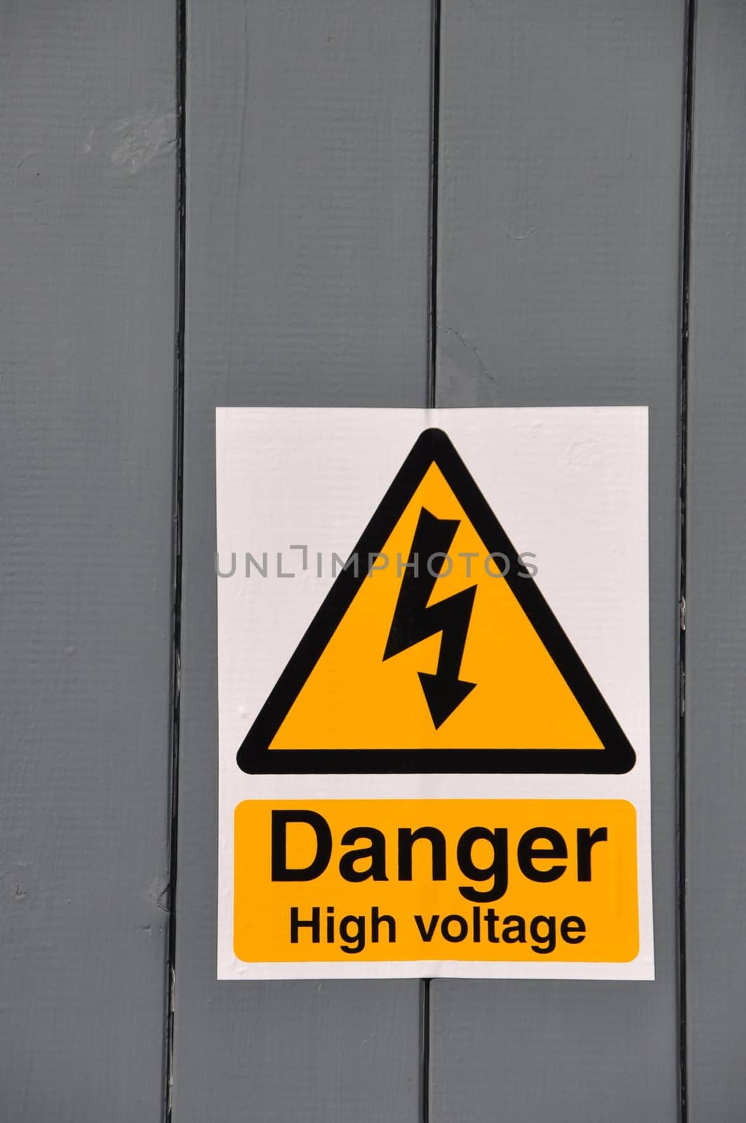 high voltage danger yellow sign on a wooden plank background