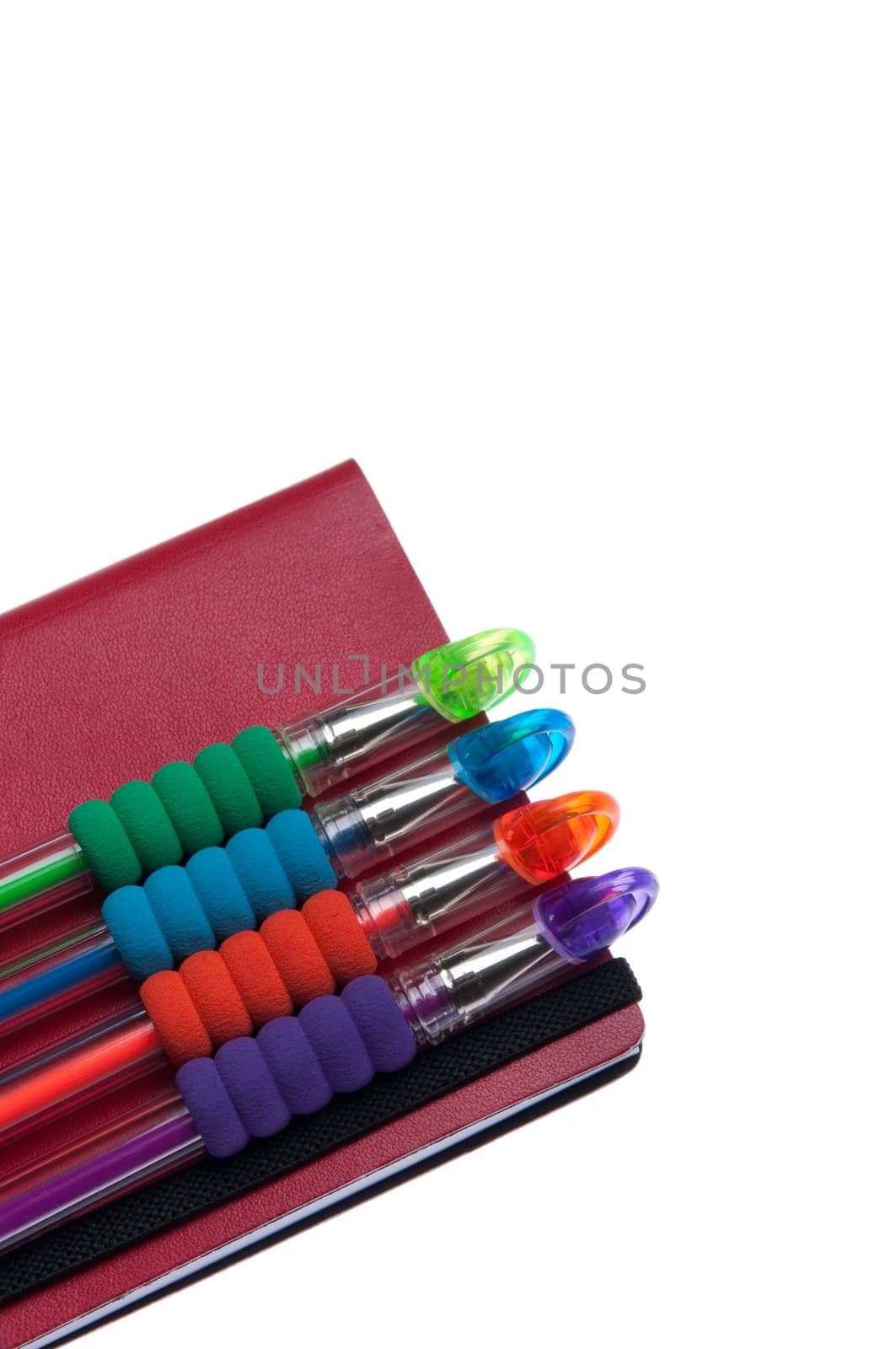 red notebook diary or agenda and colored pens lying on the top (isolated on white background)