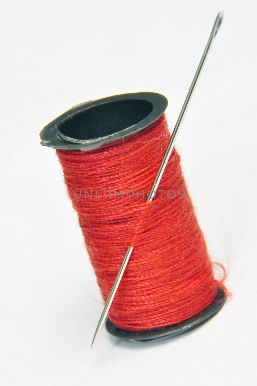 Spool of thread and needle on white background