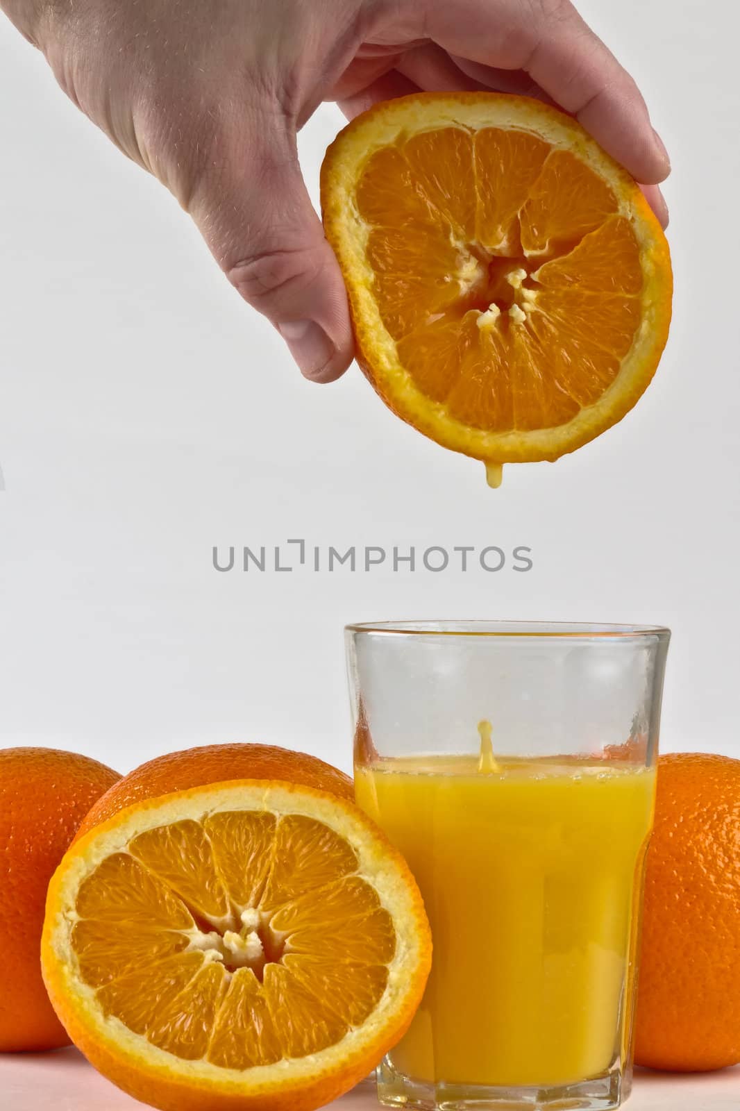 Fresh orange juice driping into glass from orange fruit.