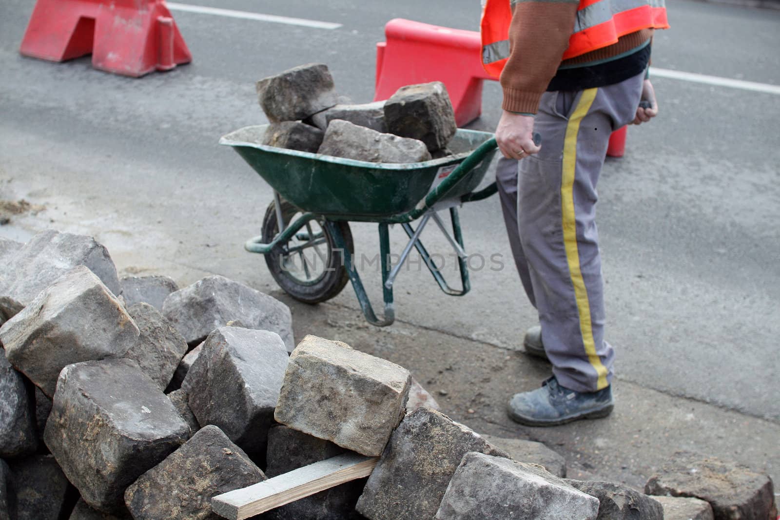 a man transports stones in a wheelbarrow, for repair the pavement