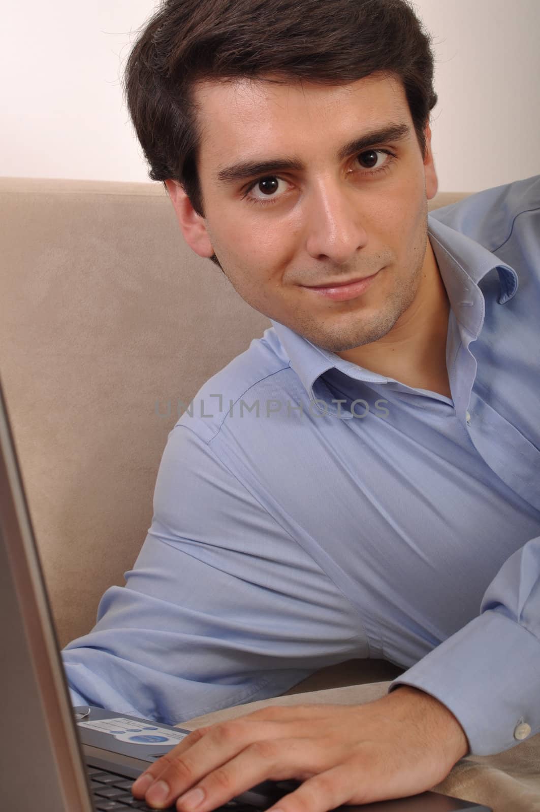 attractive young man with laptop computer lying on the couch at home