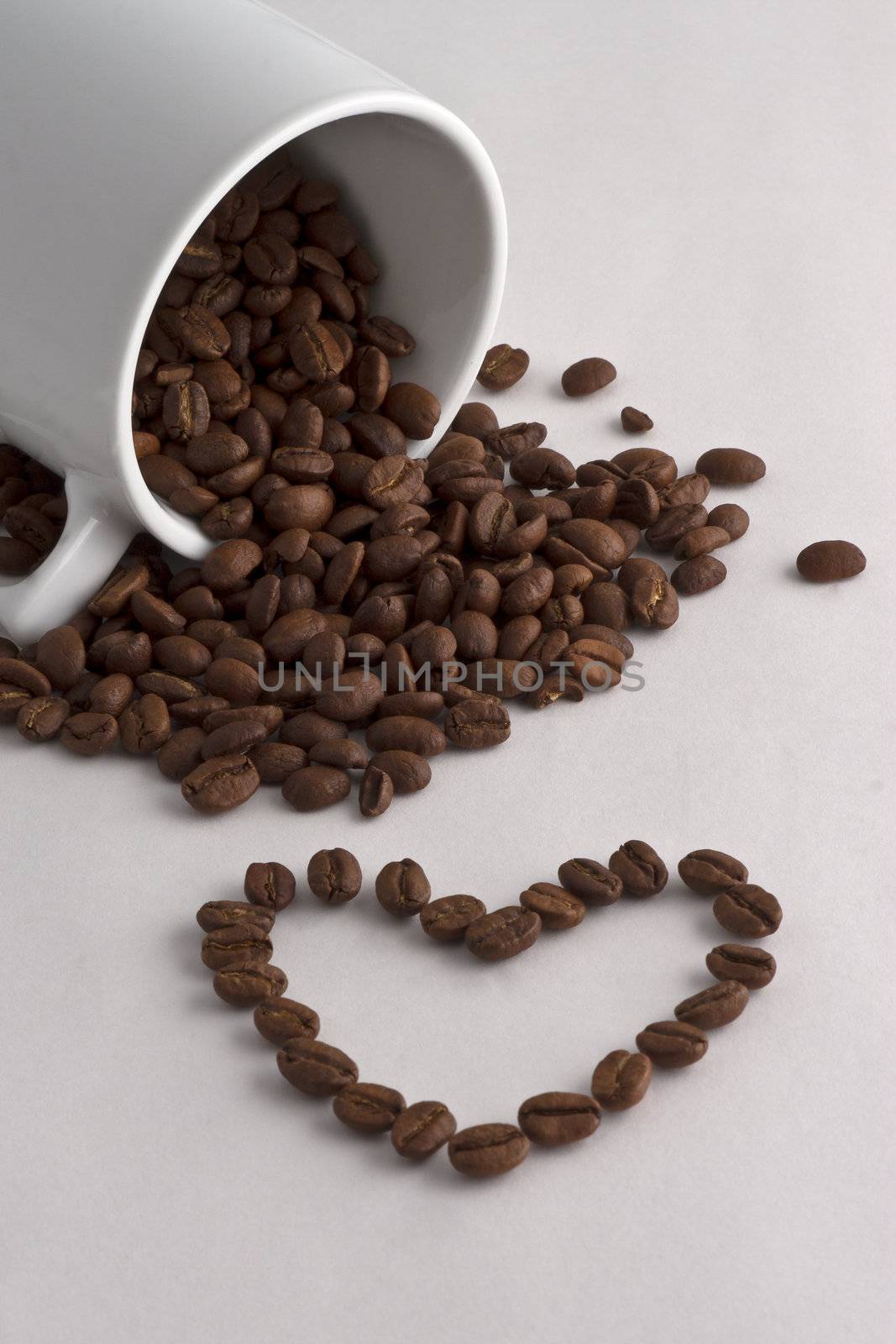 A coffee cup, coffee beans and a heart of coffee beans on white background