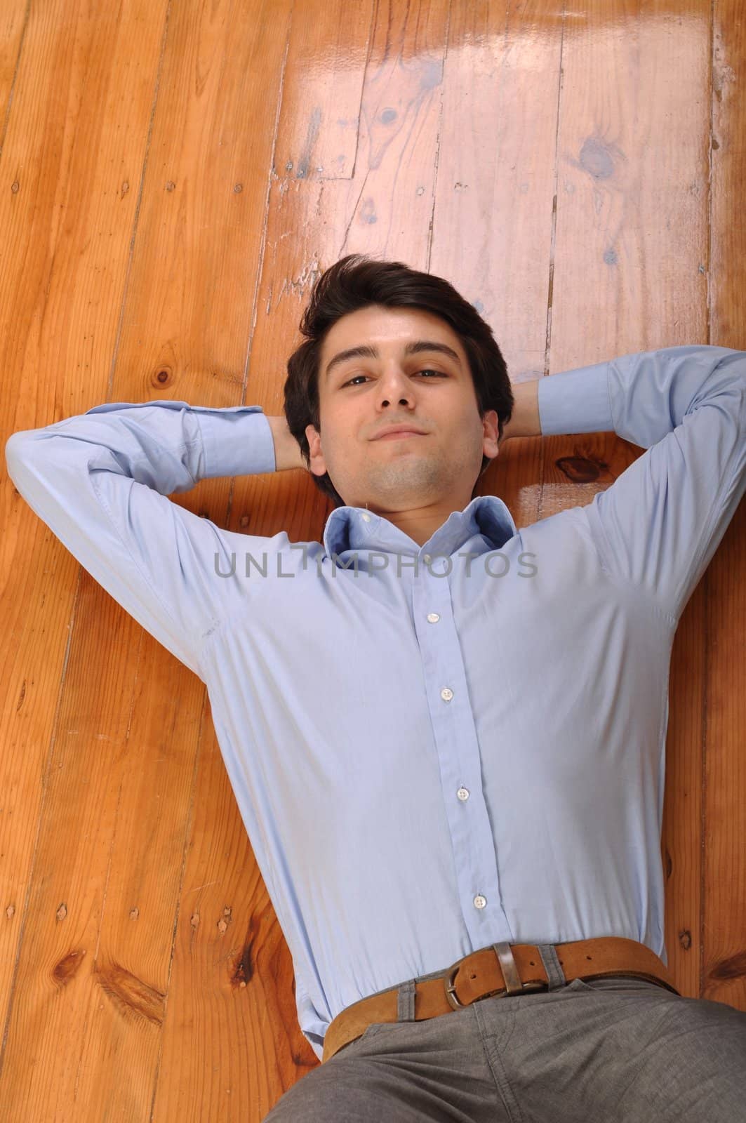 smiling attractive young man lying on wooden floor at home