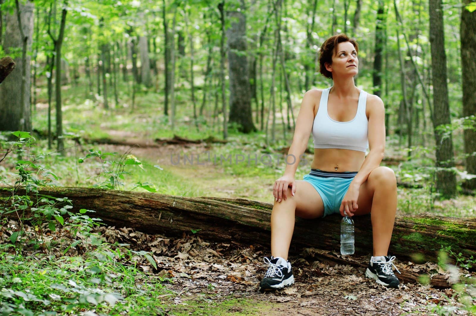 Mature woman runner resting in woods.