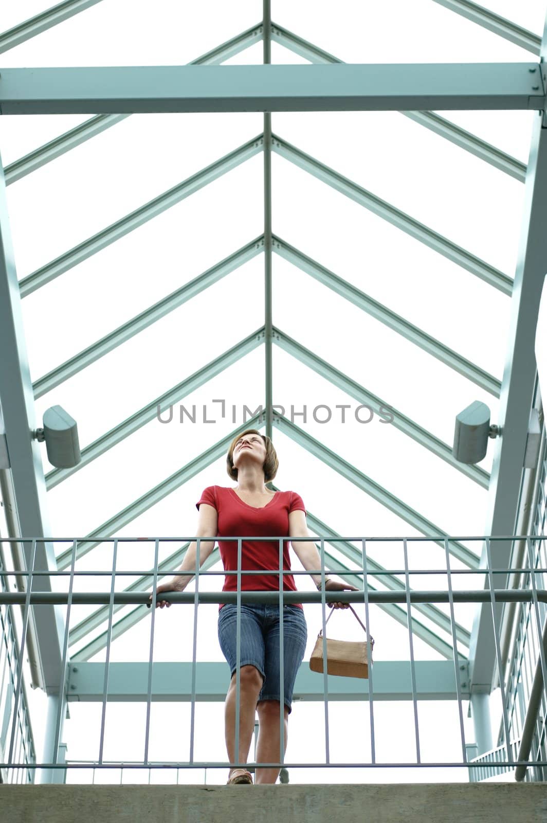 Woman standing on urban balcony looking around.