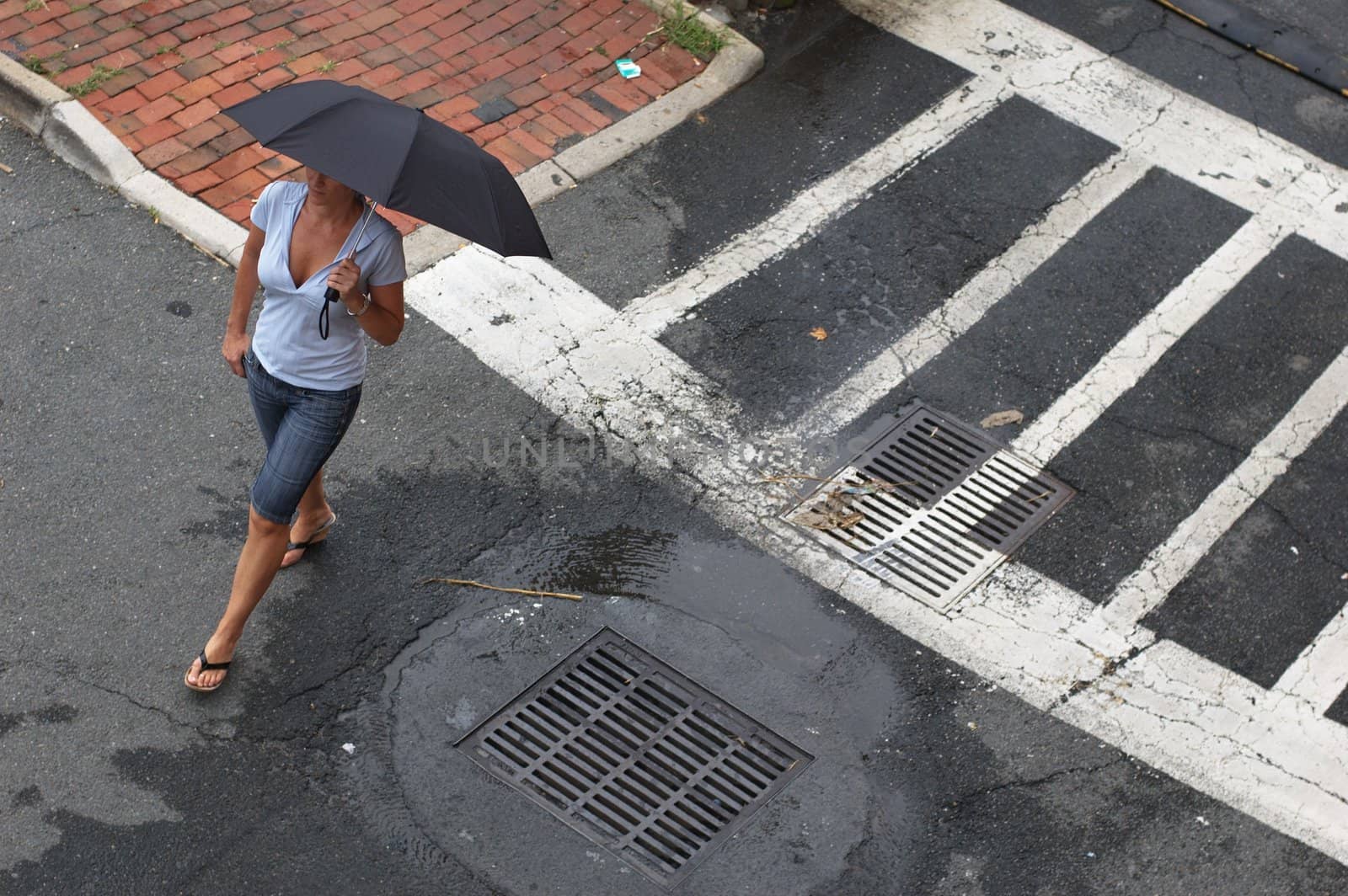 Woman walking in street with umbrella.