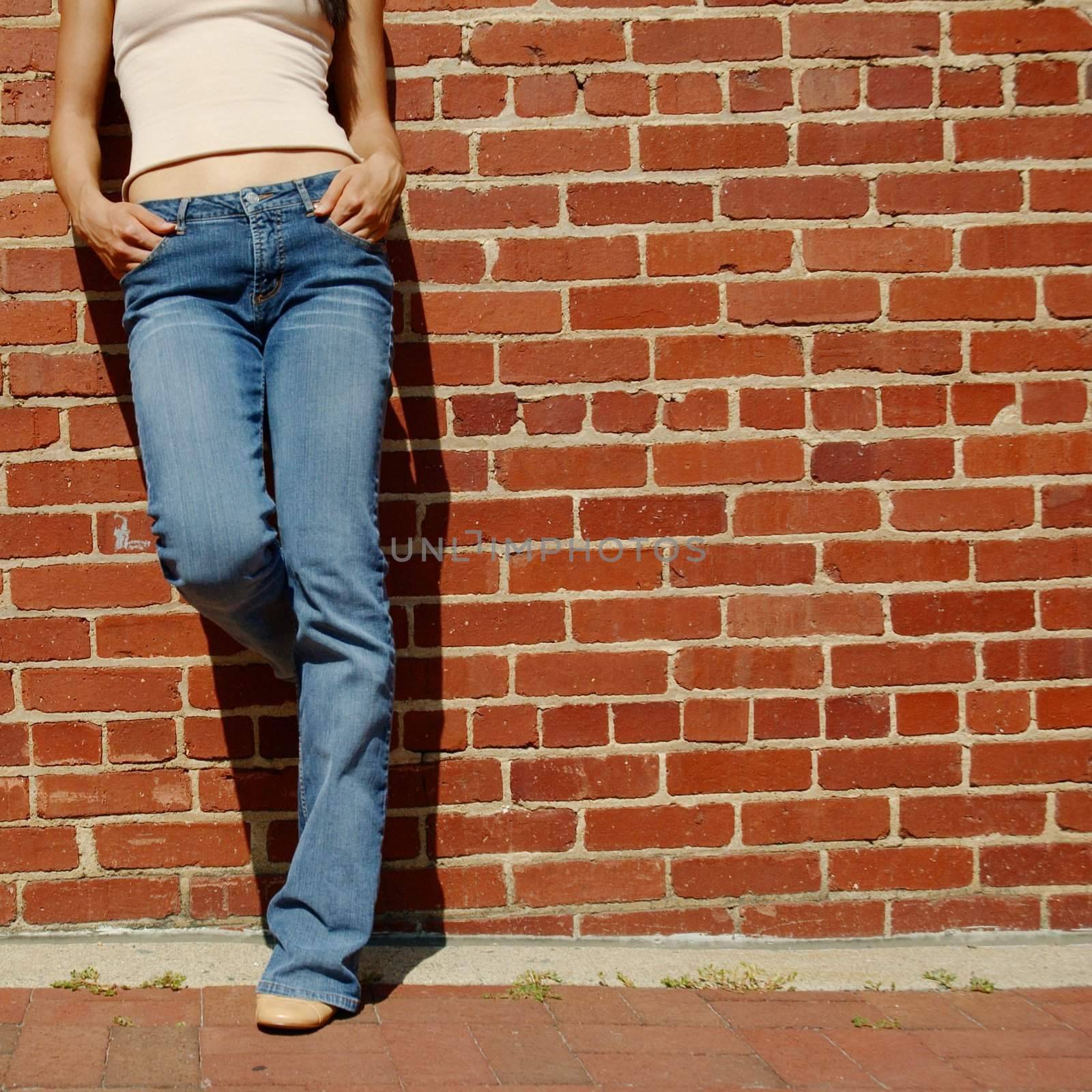 Fashionable closeups of womans mid section against brick wall.