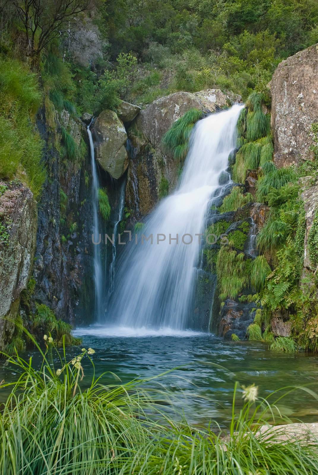 A waterfall surrounded by rocks and some vegetation.