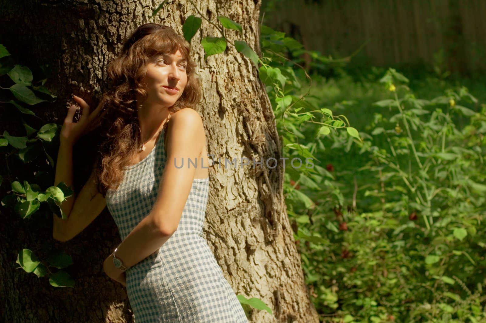 Sexy girl against tree trunk in woods.