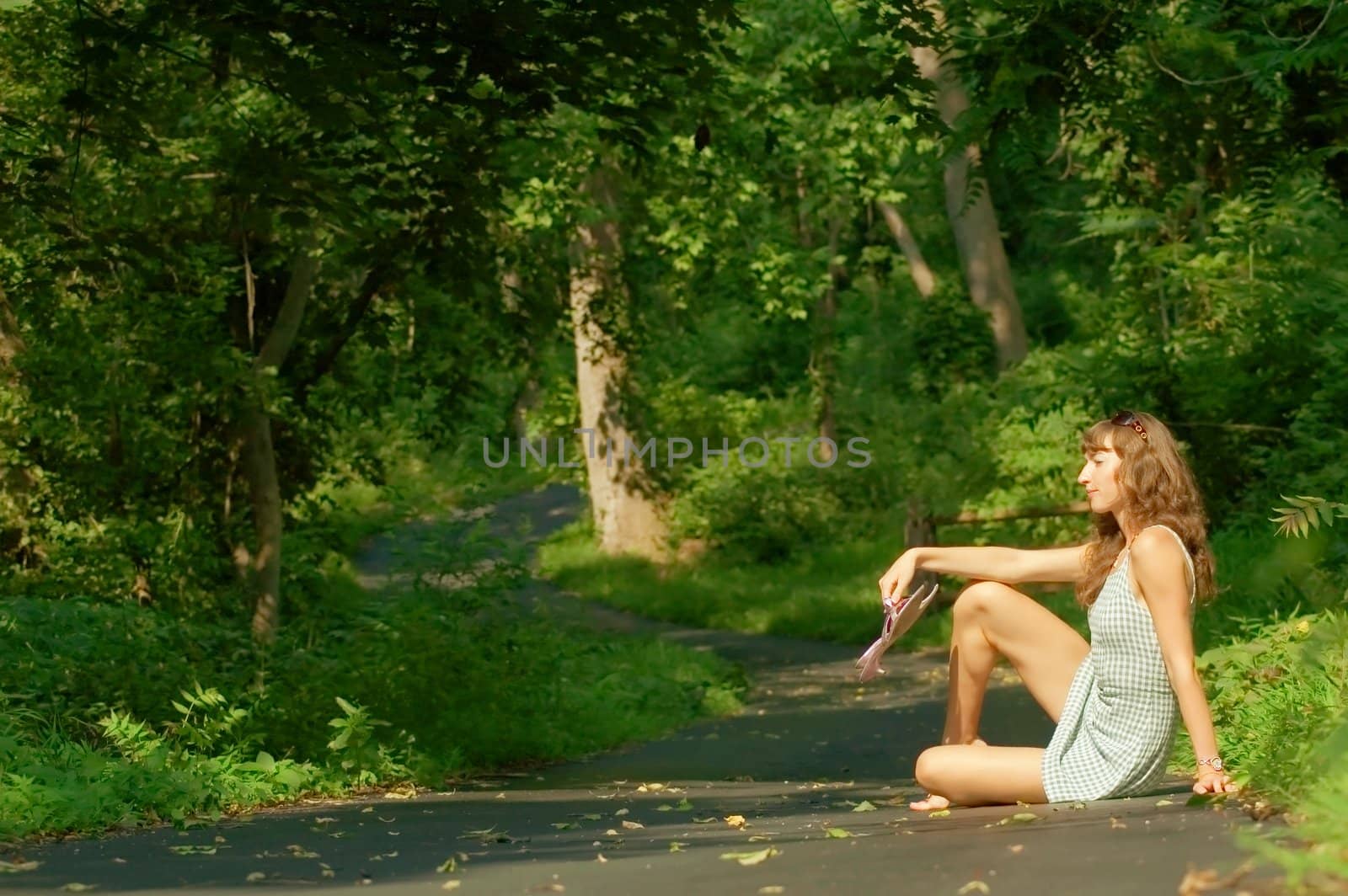 Pretty girl sitting on forest path.