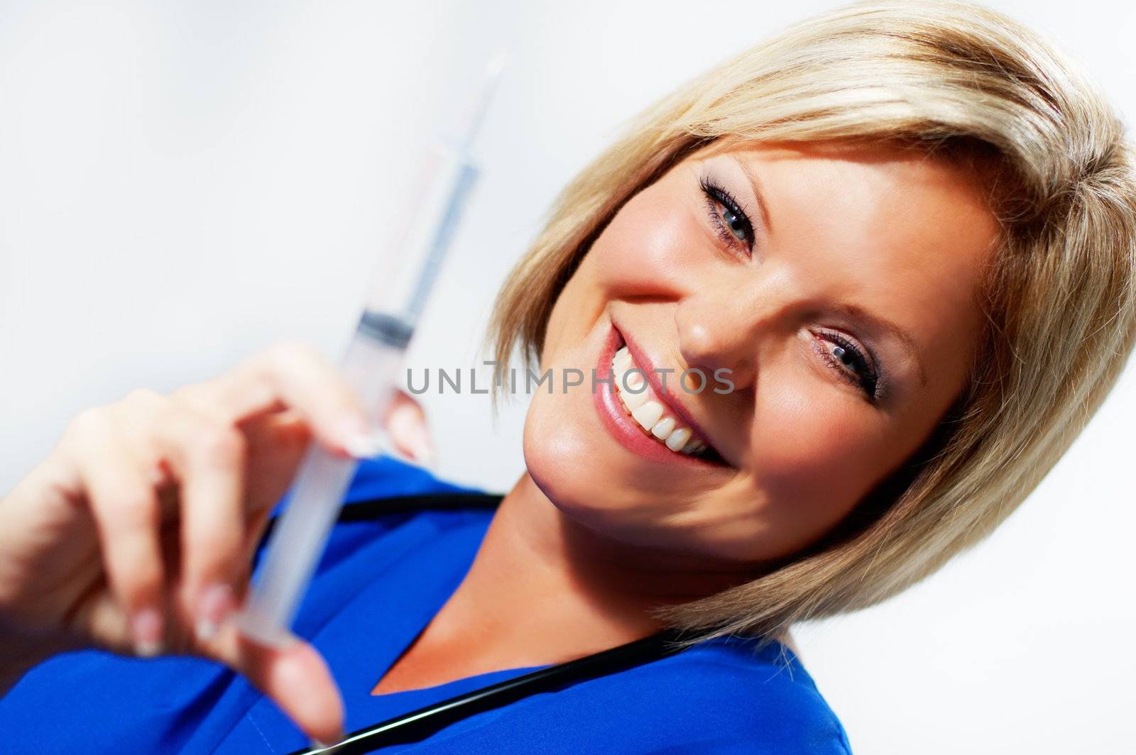 Mature woman nurse holding up a syringe and smiling.
